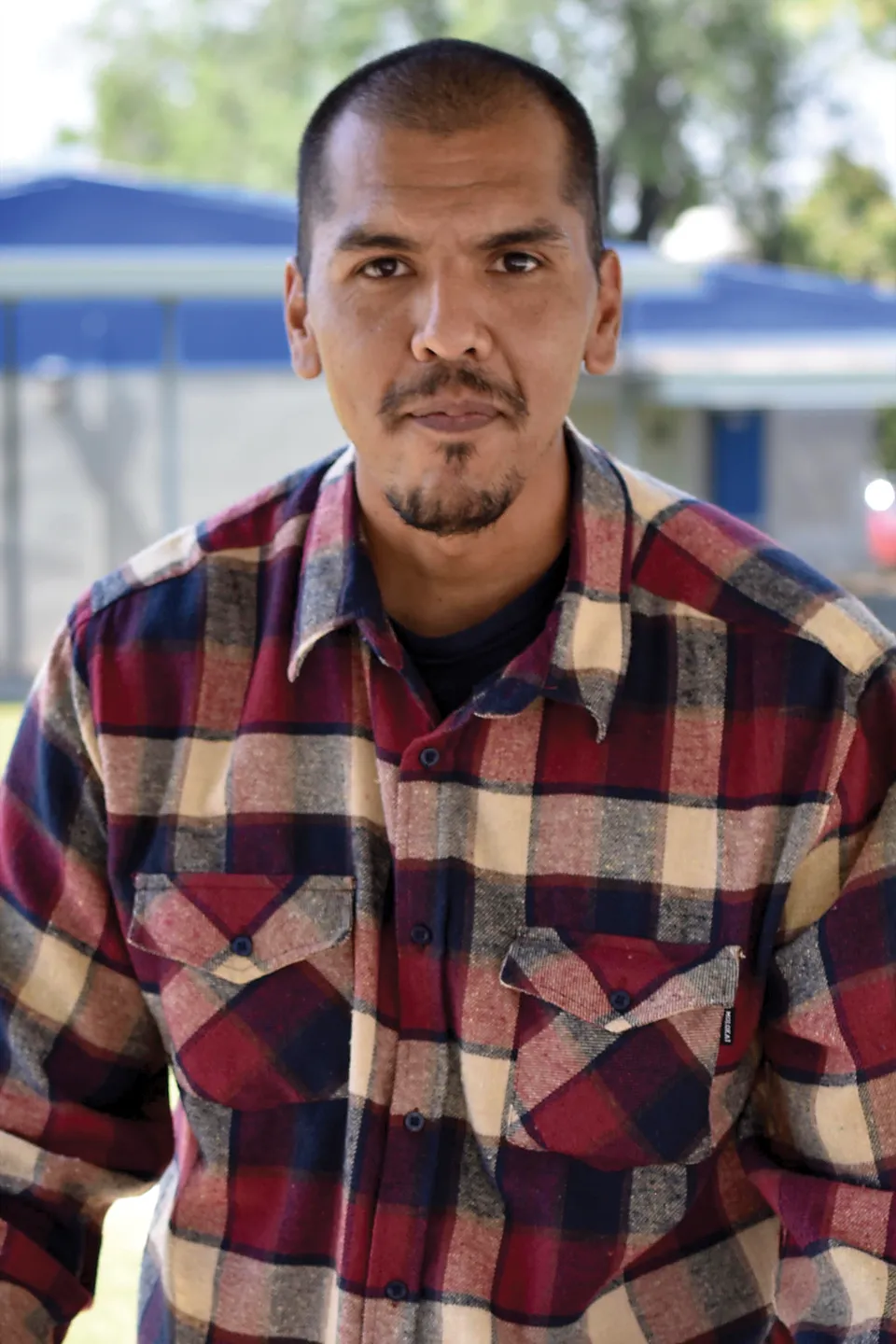 Samuel as a grown man in a plaid flannel shirt, looking into the camera.